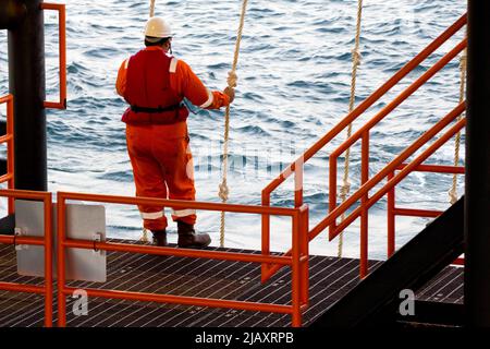 Rig-Arbeiter werden auf einem Schiff zu Offshore-Bohrinseln im Südchinesischen Meer, Brunei, transportiert. Ein Schaukelseil wird verwendet, um die Plattform zu betreten Stockfoto