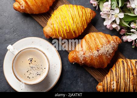 Verschiedene Croissants auf Holzbrett und Kaffee. Französisches Frühstück. Draufsicht flach liegend Stockfoto