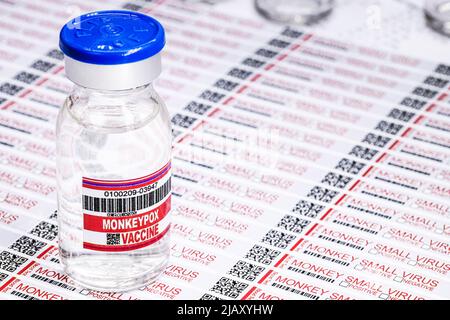 Ampulle oder Fläschchen mit Monkeypox-Virus-Impfstoff mit Gefahrenetiketten und Warnhinweisen im Hintergrund Stockfoto