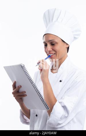 Die lateinische Köchin denkt gerne darüber nach, welches Rezept sie in ihr Notizbuch schreiben soll, isoliert auf weißem Hintergrund. Stockfoto