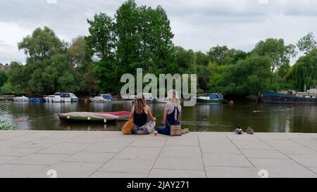 Richmond, Greater London, England, Mai 18 2022: Weibliche Freunde sitzen und plaudern am Ufer der Themse. Stockfoto