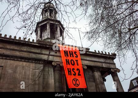 Das Banner der Kampagne „NHS Not HS2“ hängt an der St Pancras New Church entlang der Euston Road, außerhalb des Euston Bahnhofs in London - 2021 Stockfoto