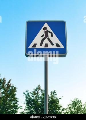 Der Fußgängerüberweg, informatives Straßenschild auf der Stange vor landschaftlich gestaltetem Hintergrund Stockfoto