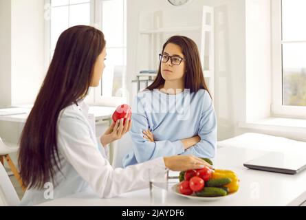 Ernährungsberaterin lehrt junge Frauen, gesunde Lebensmittel zu essen und spricht über die Vorteile von rohem Gemüse. Stockfoto