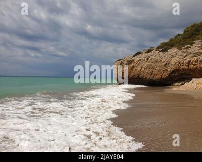 Sandstrand mit türkisfarbenem Meer vor dem Sturm, bewölktem Himmel, Sitges, Spanien Stockfoto
