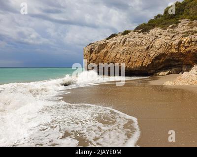 Sandstrand mit türkisfarbenem Meer vor dem Sturm, bewölktem Himmel, Sitges, Spanien Stockfoto