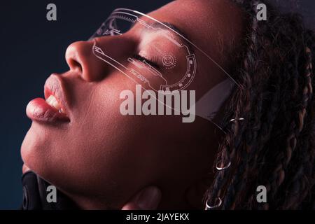 Seitenansicht einer afroamerikanischen Frau in einer intelligenten Brille, isoliert auf Dunkelgrau Stockfoto