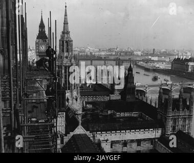 Victoria Tower, ungefiltert Nachdem sie neunzehn Jahre an ihrem Platz waren, demontieren Arbeiter Gerüste rund um den Victoria Tower, Houses of Parliament, London. Die Instandsetzungs- und Reparaturarbeiten am Turm sind gerade abgeschlossen. Im Hintergrund sieht man 'Big Ben', dessen Turm, der während des Krieges durch Bomben beschädigt wurde, nun einer ähnlichen Reparatur unterzogen wird. Ein großes Stück Schaden am Uhrenturm ist zu sehen - die Brüstung über dem Gesicht von „Big Ben“ wurde vorübergehend mit Mauerwerk repariert, was den Anschein eines „Blutergüsses“ gibt. 10. März 1954. (Foto von Evening Standard). Stockfoto