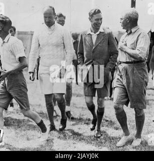 The King with Boy Cambers -- der König in Sportjacken und Shorts genießt einen Witz, während er durch das Camp läuft. H.M. der König mischte sich gestern in dem Lager in Southwold, Suffolk, unter arbeitende Burschen und öffentliche Shcoolboys, das er als Herzog von York vor 15 Jahren begann. 17. August 1937. (Foto von Topical Press). Stockfoto