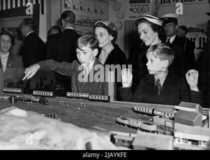 Der Herzog und die Herzogin von Gloucester Besuchen Sie die British Industries Fair: Die Herzogin von Gloucester (links) mit ihren beiden Söhnen Prinz William (zeigend) und Prinz Richard, die sich für die Miniatureisenbahn interessieren, die heute im B.I.F. zu sehen ist. Der Herzog und die Herzogin von Gloucester und ihre beiden Kinder besuchten heute die British Industries Fair in London. 05.Mai 1954. (Foto von Fox Photos). Stockfoto