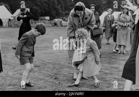 The Royal Family at Polo Tournament -- nach dem Vorbild von Königin Elizabeth am Vortag helfen Prinz Charles und Prinzessin Anne, den von den Poloponies in der Pause angepfropften unplatzierten Rasen zu beschreiten. H.M. die Königin mit ihren beiden Kindern Preise Charles und Prinzessin Anne nahmen an dem Polo-Turnier Teil, das jetzt auf Smith's Lawn im Windsor Great Park stattfindet, wo sie den Herzog von Edinburgh für eines der konkurrierenden Teams spielen sahen. 15. Juni 1955. (Foto: Sport & General Press Agency, Limited). Stockfoto