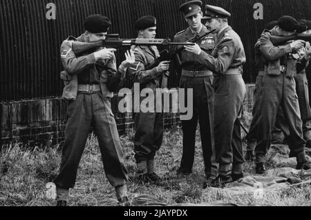 Der Herzog von Edinburgh mit der Armee - S.R.H. der Herzog von Edinburgh (mit Kamera gegenüber) hört sich eine Beschreibung des neuen F.N. Gewehr an - das jetzt bei seinem Besuch im 1. Bataillon des Wiltshire Regiments in der Salisbury Plain, Wiltshire, der britischen Armee ausgestellt wird. Der Herzog von Colonel - in - Chef des Regiments. 26. November 1954. (Foto von Sport & General Press Agency Limited). Stockfoto