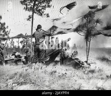 Langfeldgewehr-Sprengungen bei Target: Soldaten der 36. Field Artillery in Fort Bragg, N. C., stoppen ihre Ohren nach der Entlassung von 155mm. Das Gewehr, das längste Feld der Reichweite, wird von der US-Armee verwendet. Unter seinem Tarnnetz kann das 155mm-Gewehr Ziele in 17 Meilen Entfernung treffen. 29. März 1942. (Foto von Associated Press Photo). Stockfoto