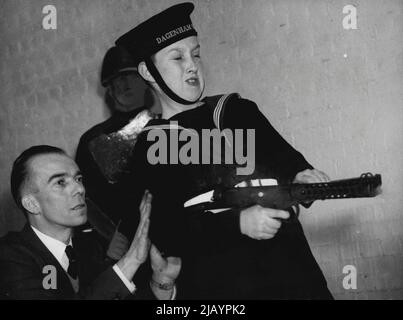 Army's New Sub-Machine Gun -- Barrie Spraggon, 12, ein Dagenham Seescout, feuert die Waffe bei der Demonstration. Dahinter steht Major Robert TURP, Chief Salesman des Sterling-Unternehmens. Das Sterling Sub-Machine-Gewehr, das kürzlich von der britischen Armee als zusätzliche Waffe für die belgische F.N. übernommen wurde Am heutigen 15. Februar wurde das Gewehr im Indoor-Bereich der Sterling Engineering Company, ihrer Hersteller, in Dagenham, Essex, demonstriert. Das Gewehr, das die stene Waffe ersetzt, ist auch im gesamten Commonwealth im Einsatz. Es wiegt sechs Pfund, feuert bis zu 575 Runden pro Minute und ist bis zu 200 ya genau Stockfoto