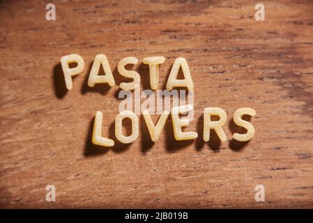 Text Pasta-Liebhaber mit Alphabet Suppe Pasta Buchstaben auf einem hölzernen Hintergrund gebildet. Stockfoto