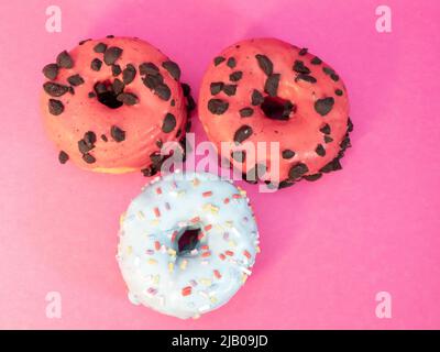 Rote und blaue Kronuts auf einem rosa Hintergrund. Hochwertige Fotos Stockfoto