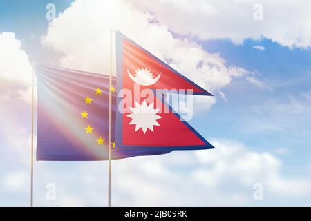 Sonniger blauer Himmel und Flaggen nepals und der europäischen Union Stockfoto