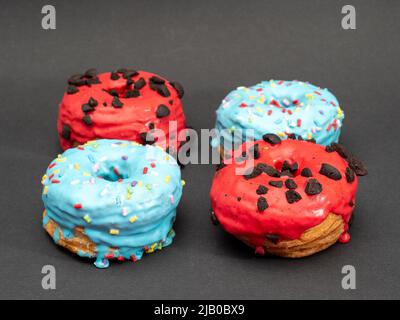 Rote und blaue Kronuts auf schwarzem Hintergrund. Hochwertige Fotos Stockfoto