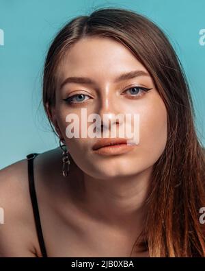 Porträt einer schönen Frau mit klarem Gesicht auf blauem Hintergrund. Vertikal Stockfoto