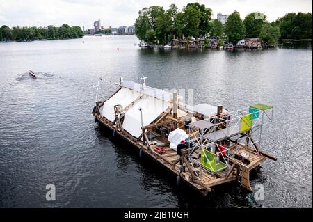 Berlin, Deutschland. 01.. Juni 2022. Das Schiff des documenta-Projekts "Citizenship" wird vom Ruder Club Tegelort über die Havel gezogen. Für das Projekt wurde die Dachkonstruktion des Berlin Center for Art and Urbanism als Floß neu gestaltet. „Citizenship“ ist mit einem Pedal- und Rudersystem sowie nachhaltigen und recycelten Antriebssystemen ausgestattet. Quelle: Fabian Sommer/dpa/Alamy Live News Stockfoto