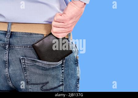 Der Mann nimmt aus der Nähe eine schwarze Handtasche aus seiner Gesäßtasche Stockfoto