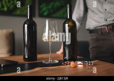 Verschiedene Weingläser und Flaschen auf Holztisch Stockfoto