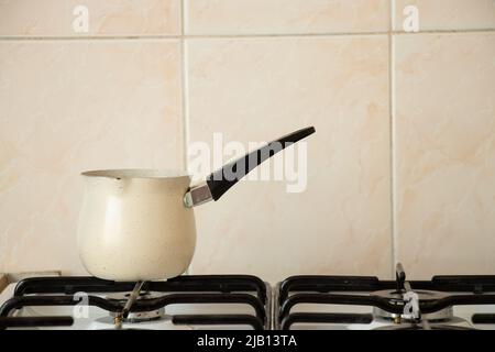 Der Kaffee-Türke steht auf einem Brenner auf einem Gasherd in der Küche zu Hause, brauen Kaffee, Kaffee am Morgen Stockfoto