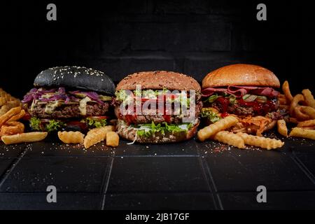 Leckere Hamburger und Pommes auf dem Tisch auf dunklem Hintergrund im Studio Stockfoto