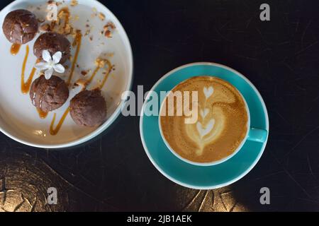 Draufsicht Coffee Latte in blauem Glas mit Bananencupcake auf weißem Teller. Ausgewählter Fokus. Pausenzeit-Konzept Stockfoto