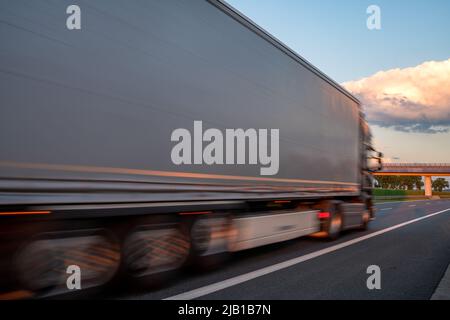 LKW auf der Autobahn während spektakulärer Sonnenuntergang, absichtliche Bewegungsunschärfe Stockfoto