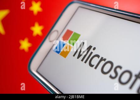 Kumamoto, JAPAN - Mär 10 2021 : Microsoft-Logo auf dem iPhone mit chinesischer Flagge im Hintergrund. Cyberangriff, IT-Technologierisiko und Konfliktkonzept Stockfoto