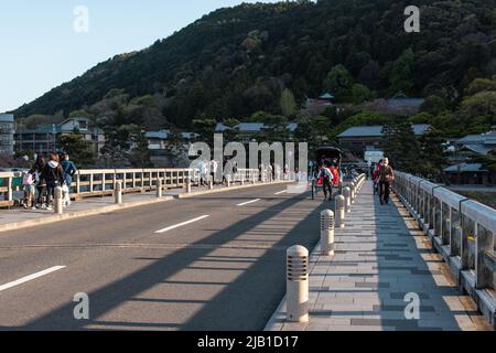 Kyoto, JAPAN - 5 Apr 2021 : die Togetsukyo-Brücke, eine Brücke über den Katsura-Fluss, die in der Dämmerung gemütlich durch das Gebiet von Saga Arashiyama fließt Stockfoto