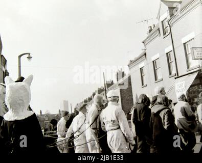 Demonstranten, darunter einige mit Masken oder Kopfmasken, nehmen 1972 an einer Anti-Rassismus-Demonstration in Leicester, England, Großbritannien und den Britischen Inseln Teil. Maskierte und behelmte Demonstranten sind mit Seilen verbunden, um andere Demonstranten in Kopfmasken zu führen. Stockfoto