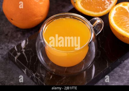 Frisch gepresster Orangensaft auf dunklem Hintergrund. Frischer Orangensaft. Nahaufnahme Stockfoto