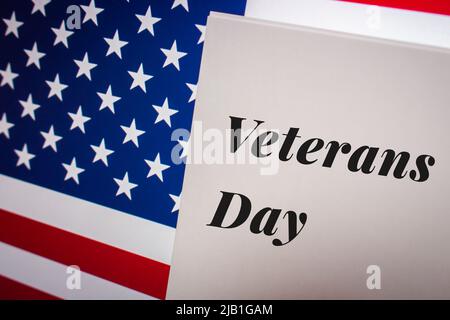 Stichwort Veterans Day, ein Bundesfeiertag in den USA, der jährlich am 11. November für die Ehrung militärischer Veteranen auf einer Karte auf einer US-Flagge begangen wird. Stockfoto