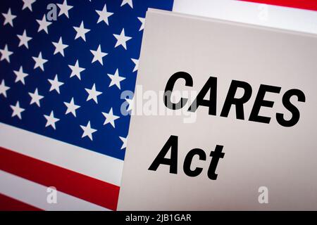 Das konzeptuelle Schlüsselwort CARES Act (Coronavirus Aid, Relief, and Economic Security Act) auf der Karte mit US-Flagge. Business, Wirtschaft, Soziales Konzept Stockfoto
