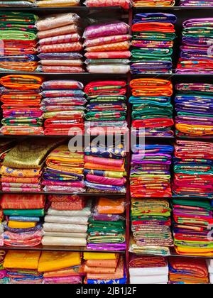 Schicke indische Sarees, fein säuberlich gestapelte bunte Seidensaris in Regalen in einem Textilgeschäft. Unglaubliches Indien. Stockfoto