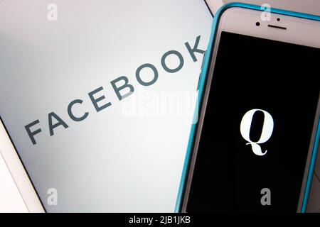 Kumamoto, JAPAN - Okt 20 2020 : das Logo von Qanon, einer rechtsextremen Verschwörungsgruppe, auf dem iPhone mit Facebook-Logo als Hintergrund. Stockfoto