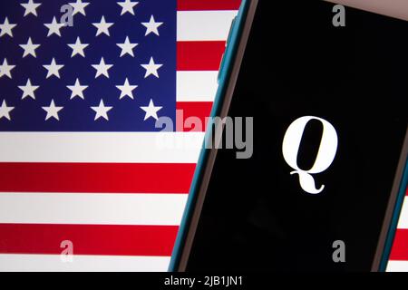 Kumamoto, JAPAN - Okt 20 2020 : Qanon-Logo auf dem iPhone mit US-Flagge Hintergrund. Qanon ist eine rechtsextreme Verschwörungsgruppe Stockfoto