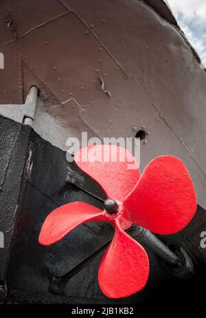 Der alte Schiffspropeller ist rot lackiert. Stockfoto