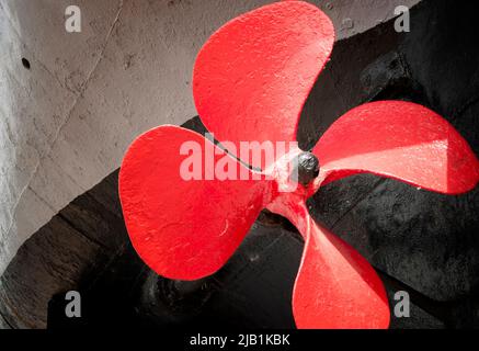 Der alte Schiffspropeller ist rot lackiert. Stockfoto