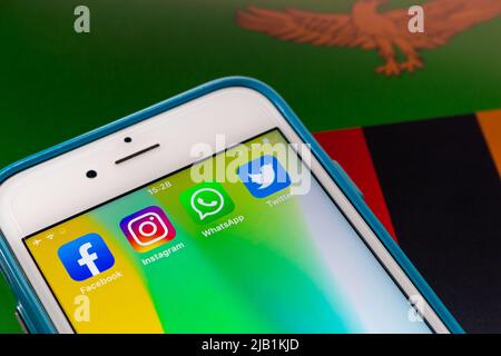 Kumamoto, JAPAN - Aug 16 2021 : Beliebte SNS (Facebook, Instagram, WhatsApp & Twitter) auf iPhone auf sambischer Flagge. Konzept der Präsidentschaftswahl Stockfoto