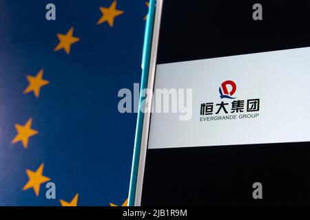 Kumamoto, JAPAN - Sep 24 2021: Chinas führender Immobilienentwickler das Evergrande Group Logo (oder die Evergrande Real Estate Group) auf dem iPhone auf EU-Flagge Stockfoto