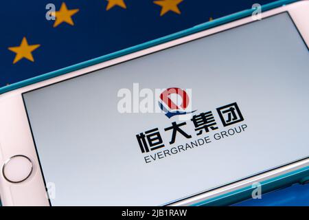 Kumamoto, JAPAN - Sep 24 2021: Chinas führender Immobilienentwickler das Evergrande Group Logo (oder die Evergrande Real Estate Group) auf dem iPhone auf EU-Flagge Stockfoto