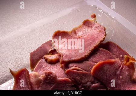 Die Scheiben geräucherter Rinderzungen in der Packung in der Plastikverpackung, die von einem lokalen Supermarkt in Japan auf dem Tisch verkauft wird. Stockfoto