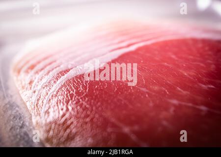 Die Scheiben des Prosciutto, eines italienischen Trockenschinken (Prosciutto crudo, Prosciutto cotto), in der Plastikverpackung, die von einem lokalen Supermarkt in Japan verkauft wird, in der Nähe halten. Stockfoto