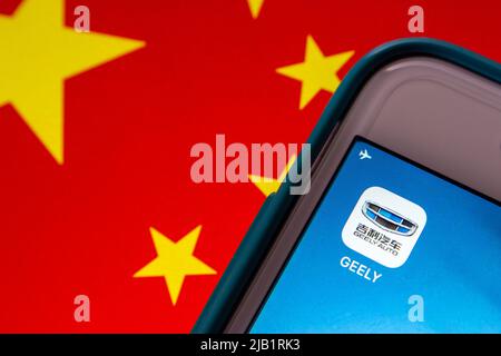 Kumamoto, JAPAN - Aug 16 2021 : Symbol des chinesischen Automobilkonzerns Geely (Marke Geely Auto) auf dem iPhone auf chinesischer Flagge. Stockfoto