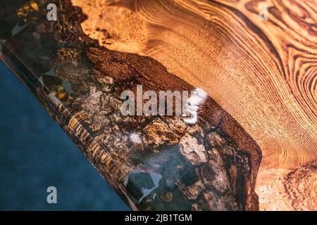 Natursteine, gefüllt mit Epoxidharz in einer hölzernen Arbeitsplatte. Handgefertigte Designermöbel. Stockfoto