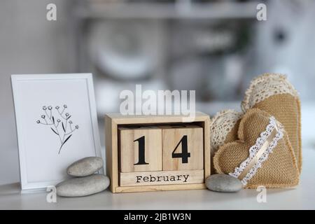 Valentinstag-Konzept. Hand machen Garn Herz neben Holzblock Kalender am Valentinstag eingestellt 14 Februar auf dem Tisch und hellen Raum Hintergrund Stockfoto