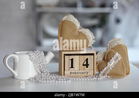 Valentinstag-Konzept. Hand machen Garn Herz neben Holzblock Kalender am Valentinstag eingestellt 14 Februar auf dem Tisch und hellen Raum Hintergrund Stockfoto